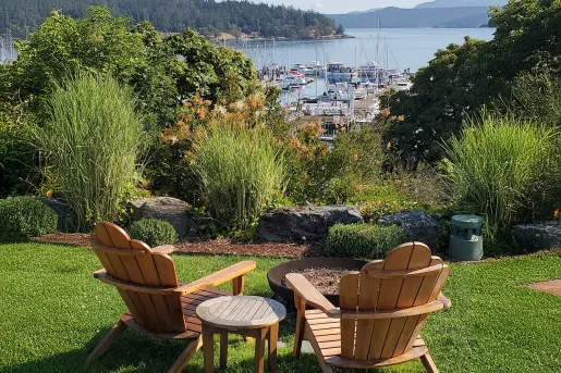 Two wooden chairs in an outdoor garden, overlooking boats and a large lake