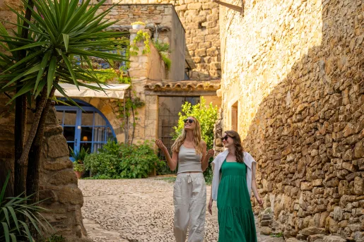 Two women smiling while walking through a stone alleyway