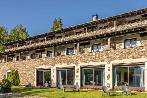 Exterior view of stone building with large windows and a grass area in front