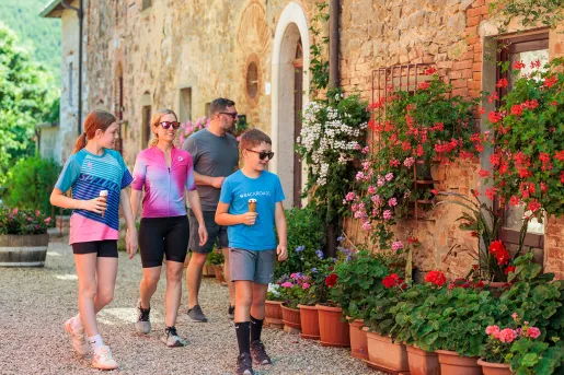 Family walking along a brick building with flowers in front, while all are holding ice cream cones