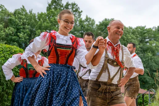 Group of men and women wearing traditional, European clothing holding hands and dancing
