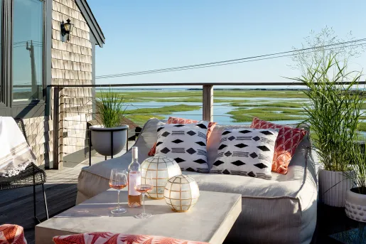 Outdoor balcony with cushioned sofas looking out towards a marsh