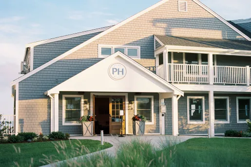 Exterior view of white and gray hotel building with a grass field in front