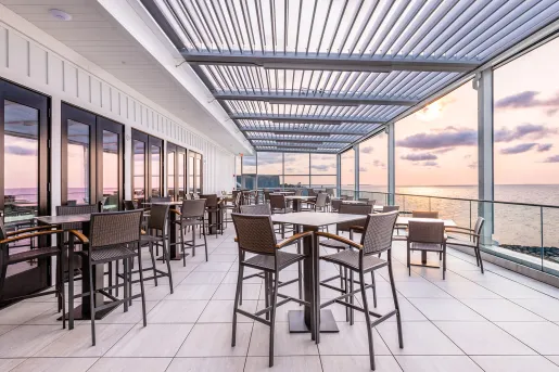 Outdoor balcony and patio with tall chairs and tables looking out to the ocean