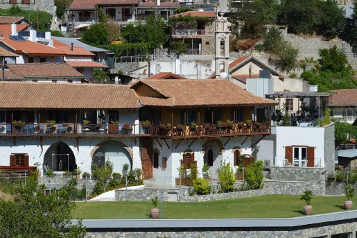 Exterior view of white building with brown balconies and roofing, with a grass field in front