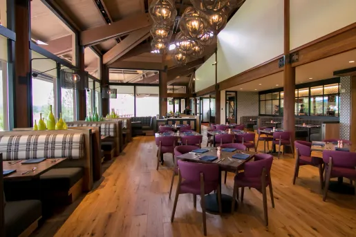 Restaurant dining area with cushioned booths and chairs around wooden tables