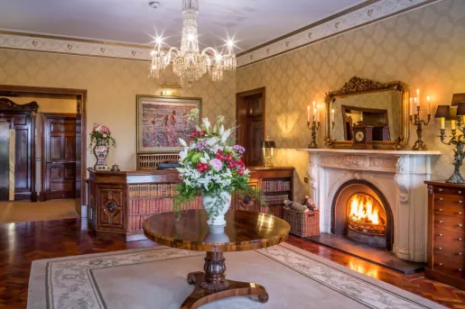 Hotel lobby with a stone fireplace and circular table, with a potted bouquet of flowers