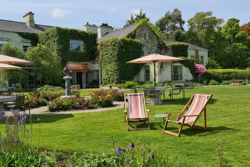 Outdoor patio and grass field with chairs, umbrellas and stone tables
