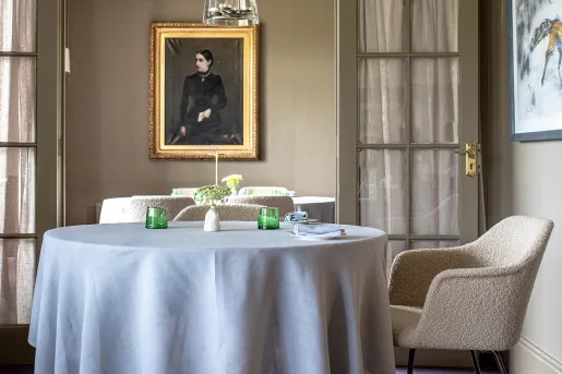 Circular dining table with gray cloth, and paintings on the wall