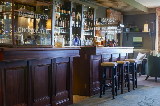 Indoor bar with redwood counters and cushioned stools, with alcohol bottles along the walls