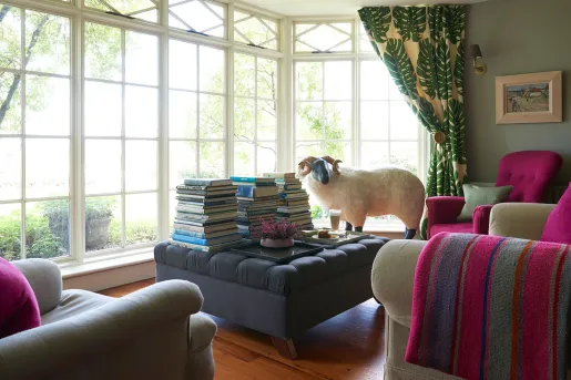 Indoor library with large, cushioned sofas and stacks of books on an ottoman
