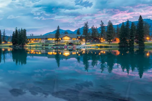 Large lake in front of a large building with pine trees surrounding