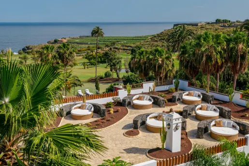 Outdoor patio with circular, white and brown chairs, looking out towards the ocean