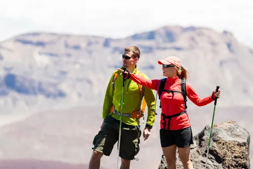 Man and woman with hiking poles, pointing and looking out to mountains