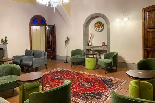 Room with a patterned, red rug on the floor and green chairs around the room