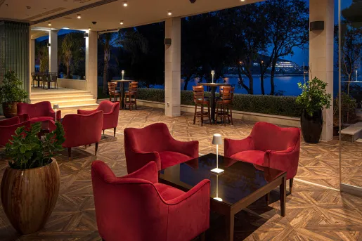 Outdoor hotel patio with red, cushioned chairs and square tables