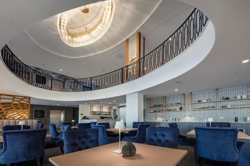 Lounge area with blue, cushioned chairs and a circular, second level above