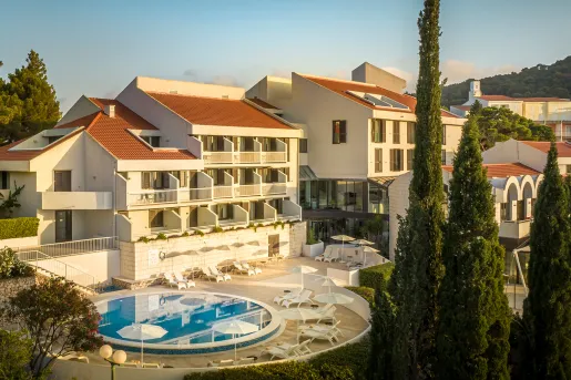 Exterior view of yellow and brown hotel building with a circular pool outside