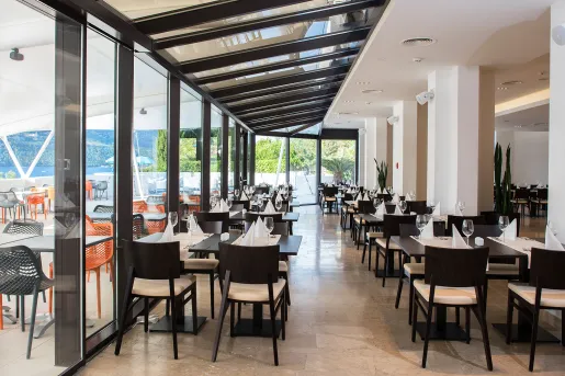 Indoor dining hall with black furniture and glass walls looking out to the ocean