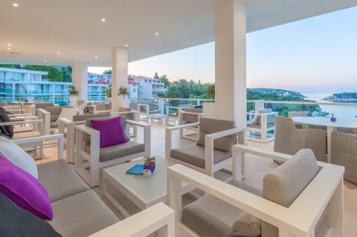 Outdoor patio with gray, cushioned chairs and a large river in the distance