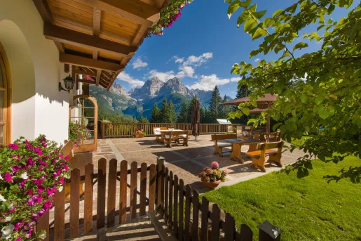Outdoor patio with wooden tables and benches, with large mountains in the distance