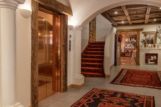 Hotel lobby with a bronze elevator and a small staircase to the right