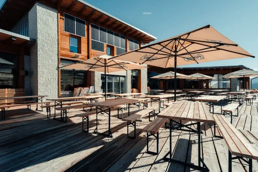 Outdoor patio with wooden tables and chairs under umbrellas