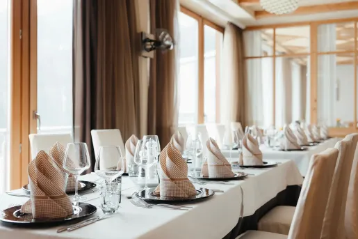 Long dining table with folded handkerchiefs and wine glasses in front of each seat
