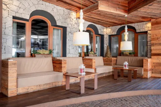 Outdoor patio with cushioned, wooden sofas and square coffee tables