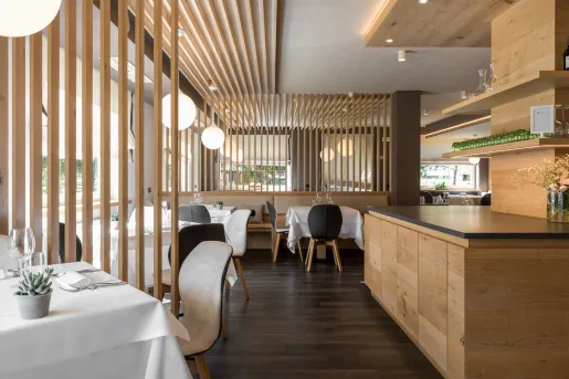 Restaurant dining hall with wooden counters and white tables with black and beige chairs