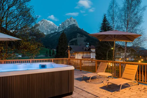 Outdoor patio with a hot tub, with views of mountains in the distance