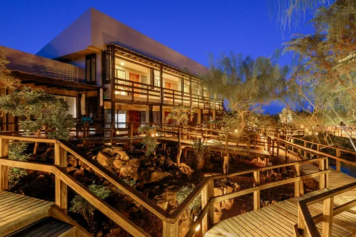 Exterior view of illuminated hotel building with wooden bridges in front