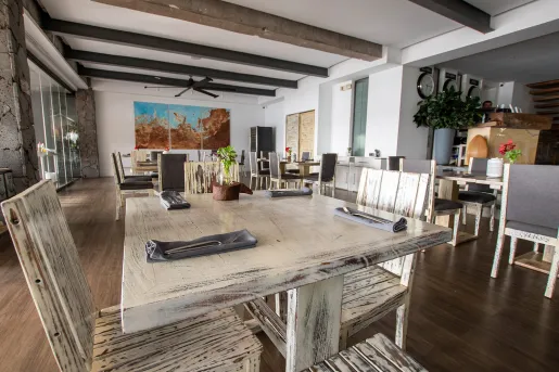 Indoor dining areas with white, wooden tables and chairs in a white room