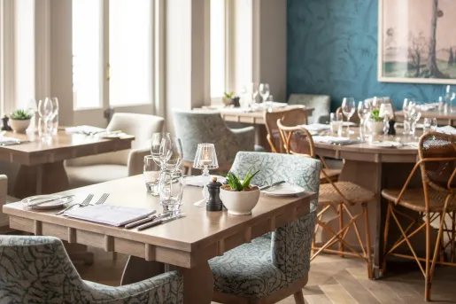 Dining room with wooden tables and clue, cushioned chairs