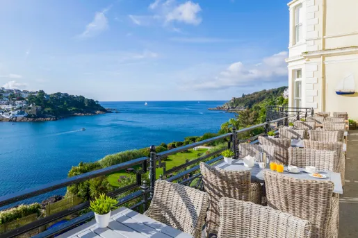 Outdoor patio with woven chairs and the ocean to the left