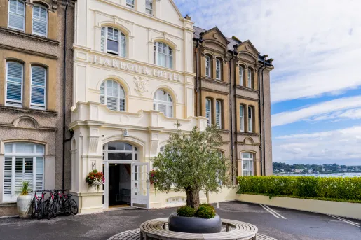Exterior view of cream-colored building with an asphalt courtyard by the ocean