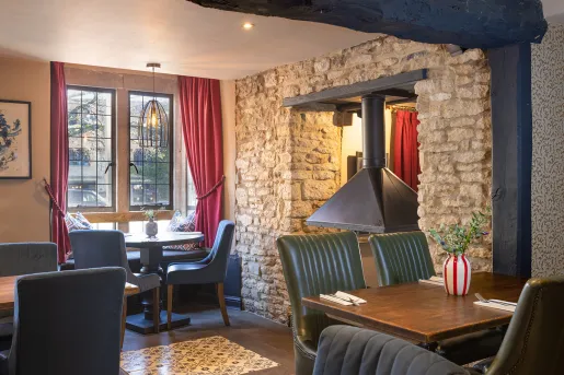 Restaurant with exposed brick walls and cushioned chairs surrounding square tables