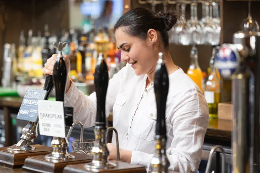 Bartender pouring a glass of beer while smiling