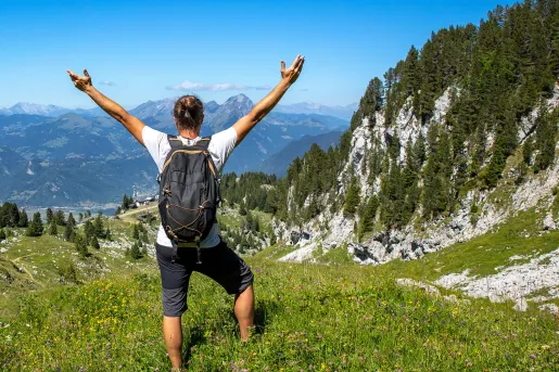 Man with his arms wide open, on top of a grassy hill