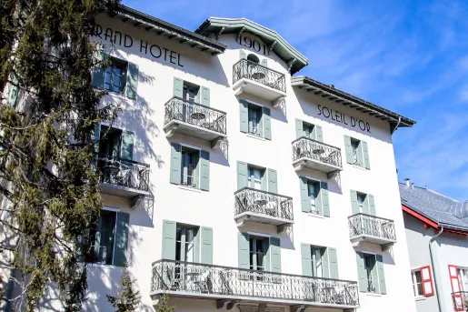 Exterior view of white hotel building with green window panes