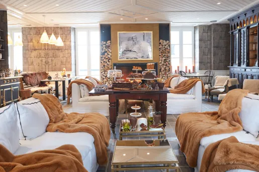 Seating area in front of a fireplace, with brown blankets on top of white couches