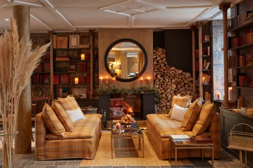 Room with a large fireplace with a giant mirror on top, with two brown, plaid couches in front