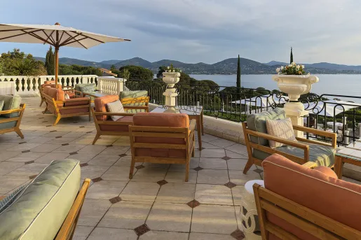 Outdoor patio with cushioned chairs, looking out to the ocean