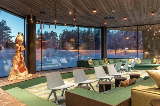 Hotel lobby with green furniture and cushioned chairs, with large windows