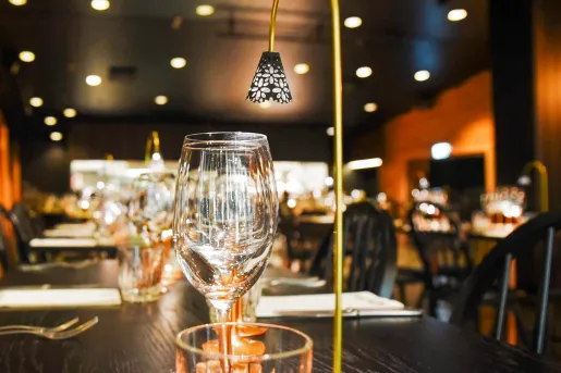 Black dining table with wine glasses and a small light fixture on top