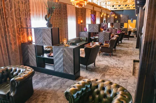 Long room with green leather couches and wooden coffee tables