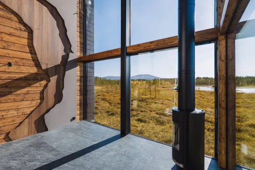 Corner of a large room with exposed wood walls and large windows