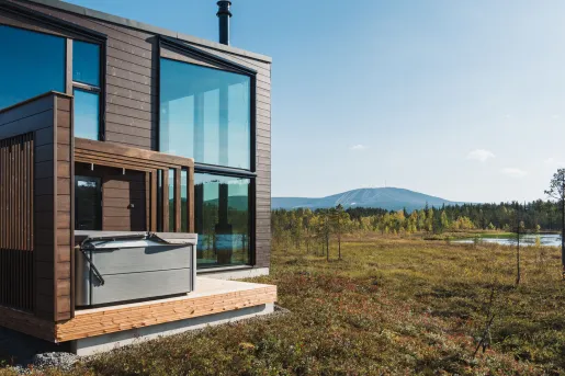 Exterior view of wooden building with large windows and a large valley in the back