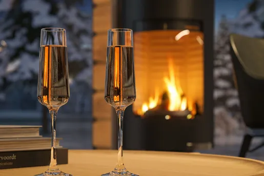 Two glasses of champagne on a table in front of a fireplace