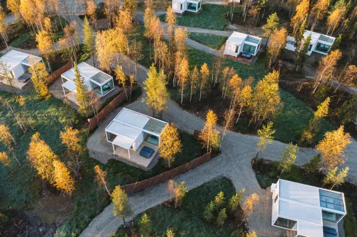 Sky view of white buildings in a valley with grass fields and yellow trees